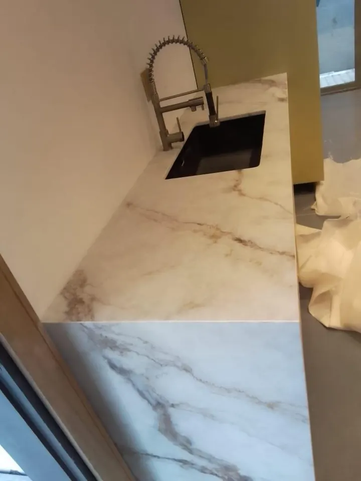 Marble-look countertop edge detail beside a black sink