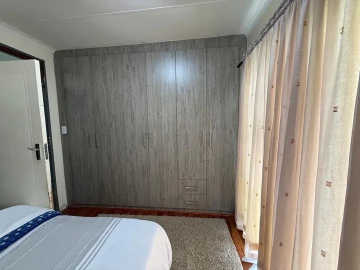 Grey oak-finish built-in wardrobe across a bedroom wall