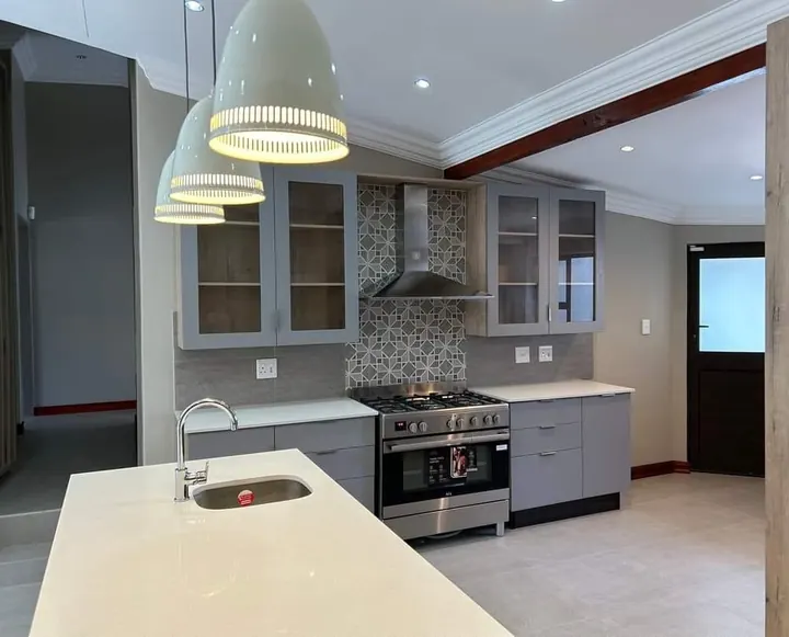 Grey kitchen cabinets with glass-front wall units and island