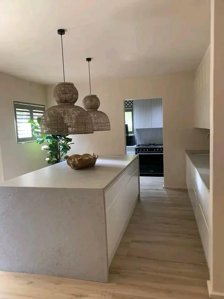 Kitchen island with stone-look worktop under woven pendant lights