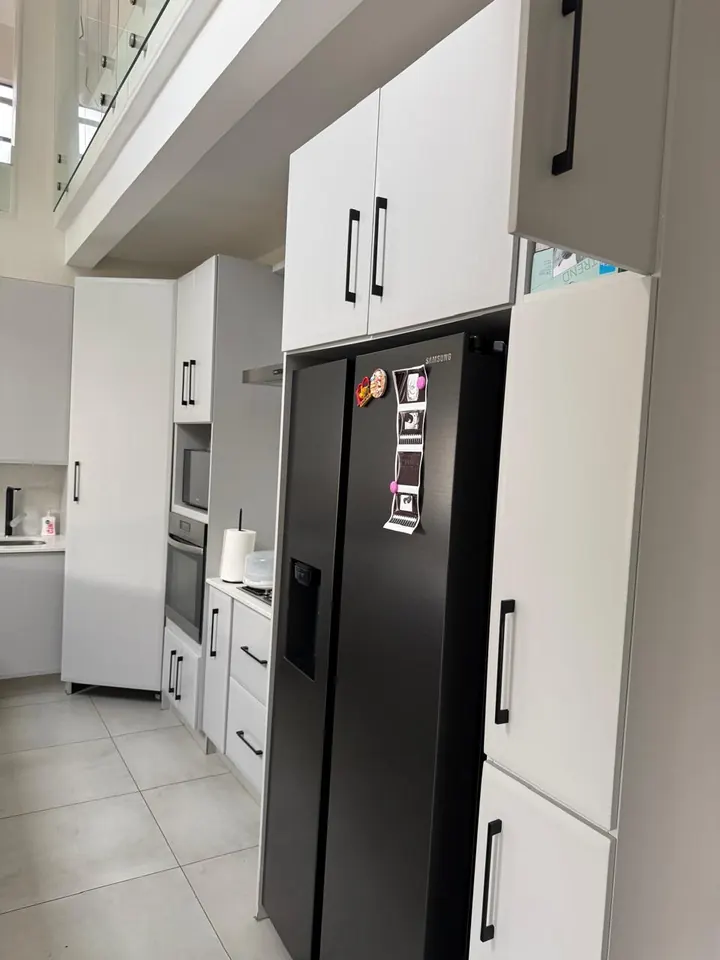 Tall white kitchen units built around a double-door fridge