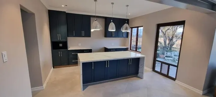 Navy kitchen units and island with pendant lights